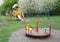 Empty outdoor playground for children with a slide, carousel, pull up, chin up bar in the park with blooming trees in the