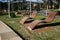 Empty outdoor wood slat chaise lounge chairs hovering above grass in park at University of Sydney, Australia