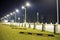 Empty parking lot on green lawn brightly illuminated by street lamps along road on dark night sky copy space background