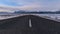 Empty paved ring road in the south of Iceland near Skaftafell with the snow-covered foothills of Ã–rÃ¦fajÃ¶kull.