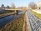 Empty paved river embankment with shadow from fence.