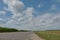 An empty paved road passes through a cornfield. Corn grows on the side of the road. Empty background, space for text. New asphalt