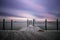 An empty peaceful dock within a marina as clouds streak across the sky. Still water, serene and calm scene.