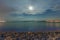 Empty pebble beach at night illuminated by the moonlight