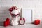 Empty photo frame with female plaster head with heart shaped glasses, flowers, alarm clock and candles against the white brick