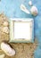 Empty photo frame with sea shells on sand over blue paper. Travel, beach vacation concept