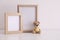Empty photo frames and toy bear on table near white wall. Space for design