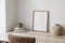Empty picture frame mockup in boho modern minimalist interior. Wooden table, blurred rattan chair. Textured vase. Cup of