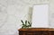 empty picture frame mockup on wooden table and ruscus plants.