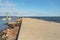 Empty pier on a beach concrete cement texture with copy space room for text on the dock, blue sky and water, New England summer,