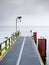 Empty pier in harbor. Steel grate board. Black cormorant sit on lamp.