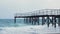 Empty pier with rusty iron poles  against blue sea waves. Old rusty pier on sea. Beautiful seascape with cloudy sky