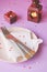 Empty pink plate, cutlery, hearts, candlesticks and red gift on pink-purple background. St. Valentine`s Day table setting concept