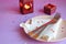 Empty pink plate, cutlery, hearts, candlesticks and red gift on pink-purple background. St. Valentine`s Day table setting concept