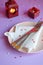 Empty pink plate, cutlery, hearts, candlesticks and red gift on pink-purple background. St. Valentine`s Day table setting concept