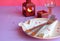 Empty pink plate, cutlery, hearts, candlesticks, wine glasses and red gift on pink-purple background. St. Valentine`s Day table