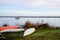 Empty plastic recreational kayaks for rent hire stored on green grass lake beach