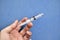 Empty plastic syringe with no needle in hand on a blue background