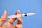 Empty plastic syringe with no needle in hand on a blue background