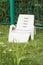 Empty plastic white chaise longue stands on the green grass, in a private area, fenced off by a hedge, rest in a hotel at the