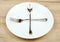 Empty plate with crossed fork and spoon on wooden table