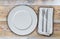 Empty plate with cutlery on untreated wood background