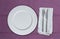 Empty plate and cutlery on violet cloth