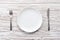 Empty plate fork knife silverware white wooden table background