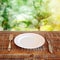 Empty plate with knife and fork over garden background