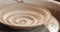 An empty plate with relief rotates on the pottery wheel, close up. Winding clay structure. Handmade, craft. White clay.