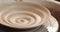 An empty plate with relief rotates on the pottery wheel, close up. Winding clay structure. Handmade, craft. White clay.