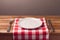 Empty plate with tablecloth and silverware on wooden table