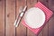 Empty plate on tablecloth on wooden table. View from above