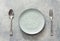 Empty plate with utensils on stone background