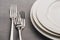 Empty plates with forks on grey linen tablecloth