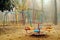 Empty playground with carousels and swings in misty park