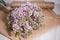 Empty postal envelope and bouquet of lilac flowers on the white wooden background, copy space. Top view.