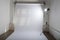 An empty professional photo studio with clean and simple photographic equipment setup of white, plain paper backdrop