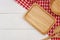 Empty rectangle wooden plate with spoon, fork and red gingham tablecloth on white wooden table.