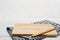 Empty rectangle wooden serving board with butter knife and grey gingham tablecloth on white wooden table.