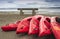 Empty red plastic recreational kayaks for rent or hire, stored on sandy beach after hours on a rainy day. Crescent Beach, Surrey,