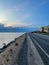 Empty road with a coast on the one side and a cycleway on another. Cloudy sunset view.