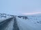 Empty road covering by white snow and some dry grass at side way with cloudy climate in winter.