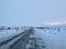 Empty road covering by white snow and some dry grass at side way with cloudy climate in winter.