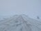 Empty road covering by white snow and some dry grass at side way with cloudy climate in winter.