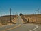 Empty road over a hill and railroad tracks with windmills in the background