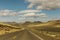 Empty Road Winding Through A Hilly Landscape 