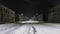 An empty roadway in a winter city at night. Traffic light blinks orange. Urban lighting. Weather conditions. Old three