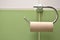 Empty roll on toilet paper holder with white and green tiles in background