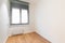 Empty room with bright window, laminate flooring and newly painted white walls in refurbished flat